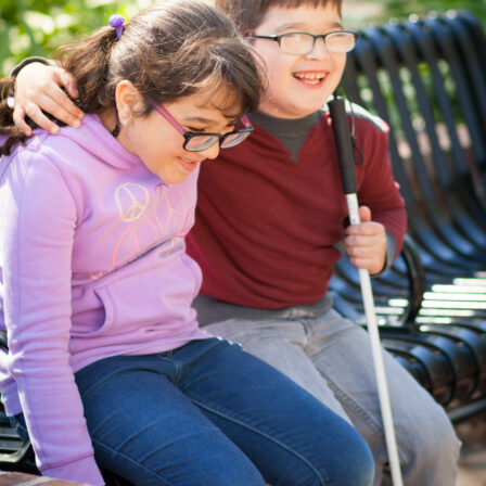 children laugh sitting on a park bench